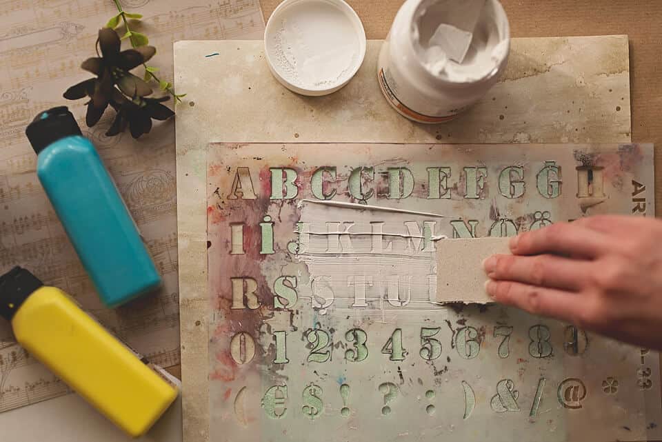 een foto van het gebruik van een STENCIL en GESSO op de omslag van het DIY ART JOURNAL