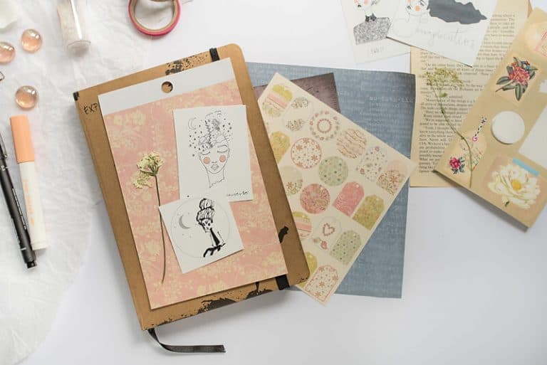 A PHOTO OF AN ART JOURNAL, PAPER CUT-OUTS, SCRAPBOOK PAPERS, STICKERS, WASHI TAPE AND A PEN. A PHOTO OF SUPPLIES FOR AN ART JOURNAL PAGE
