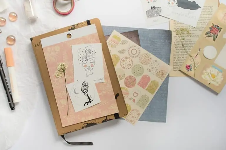A PHOTO OF AN ART JOURNAL, PAPER CUT-OUTS, SCRAPBOOK PAPERS, STICKERS, WASHI TAPE AND A PEN. A PHOTO OF SUPPLIES FOR AN ART JOURNAL PAGE