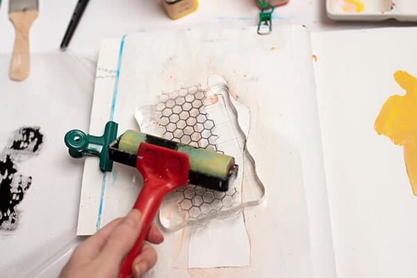 applying acrylic paint on a stamp with a brayer