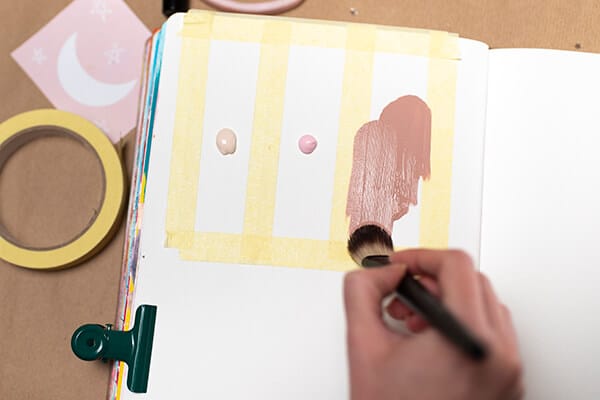 painting with paintbrush over masking tape