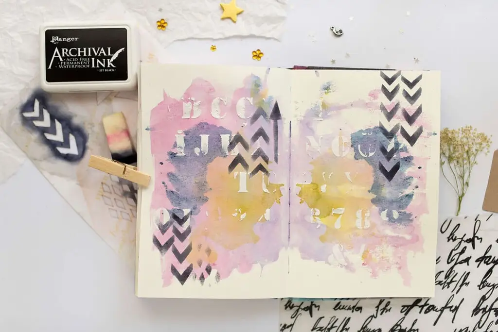 art journal spread with stencil marks and ink