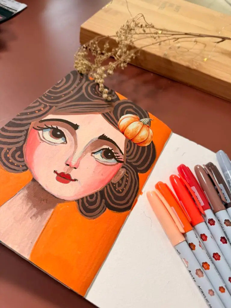 an art journal of a fall whimsical face using Arrtx acrylic markers