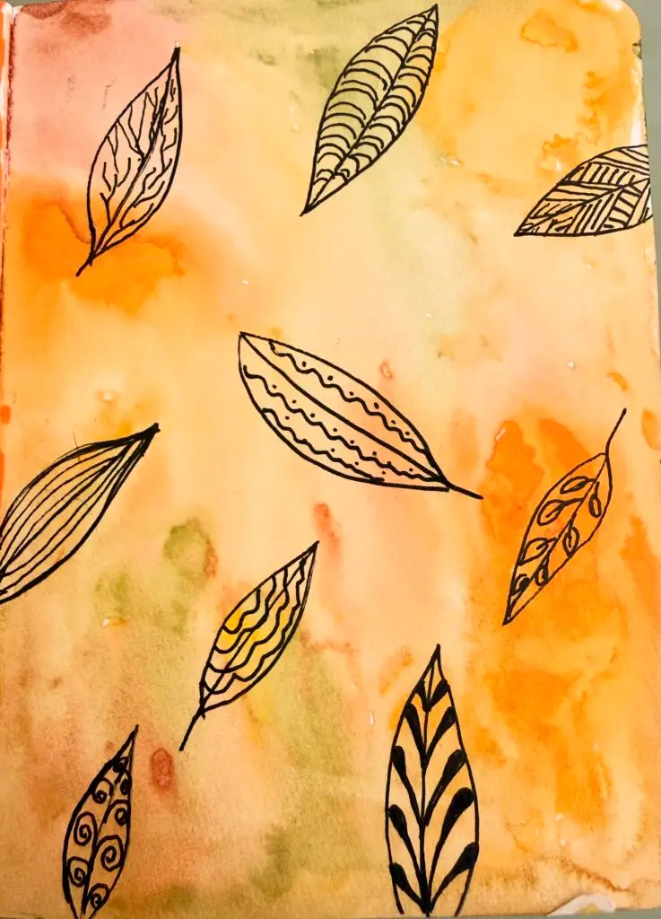 an art journal of different fall leaves with doodles inside each one.